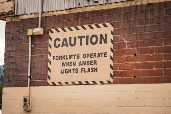 Caution sign about forklifts on a brick wall