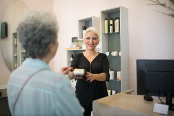 Salon receptionist serving a client at the front desk
